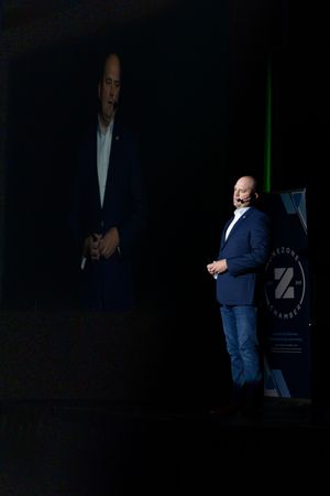 A series of dark photos showing someone in business attire walking across a dimly lit stage with dramatic lighting.