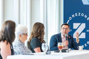 Panel discussion at business conference with speakers seated at table with beverages and microphones.