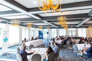 A large corporate conference room filled with attendees during a business presentation or meeting.