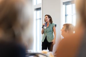 A speaker addresses an audience during a business presentation in a bright conference room.