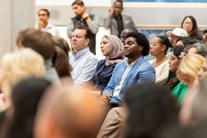Diverse audience members sit attentively in rows during a presentation or conference event.
