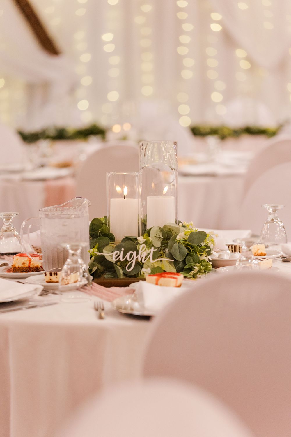White wedding reception table settings with centerpieces and glowing candlelight create an elegant dining atmosphere.