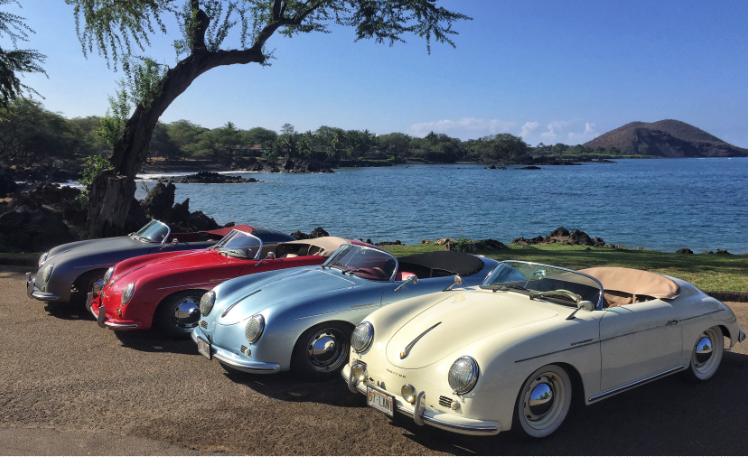 Four vintage Porsche convertibles parked along a scenic Hawaiian coastal road on Maui, Hawaii.