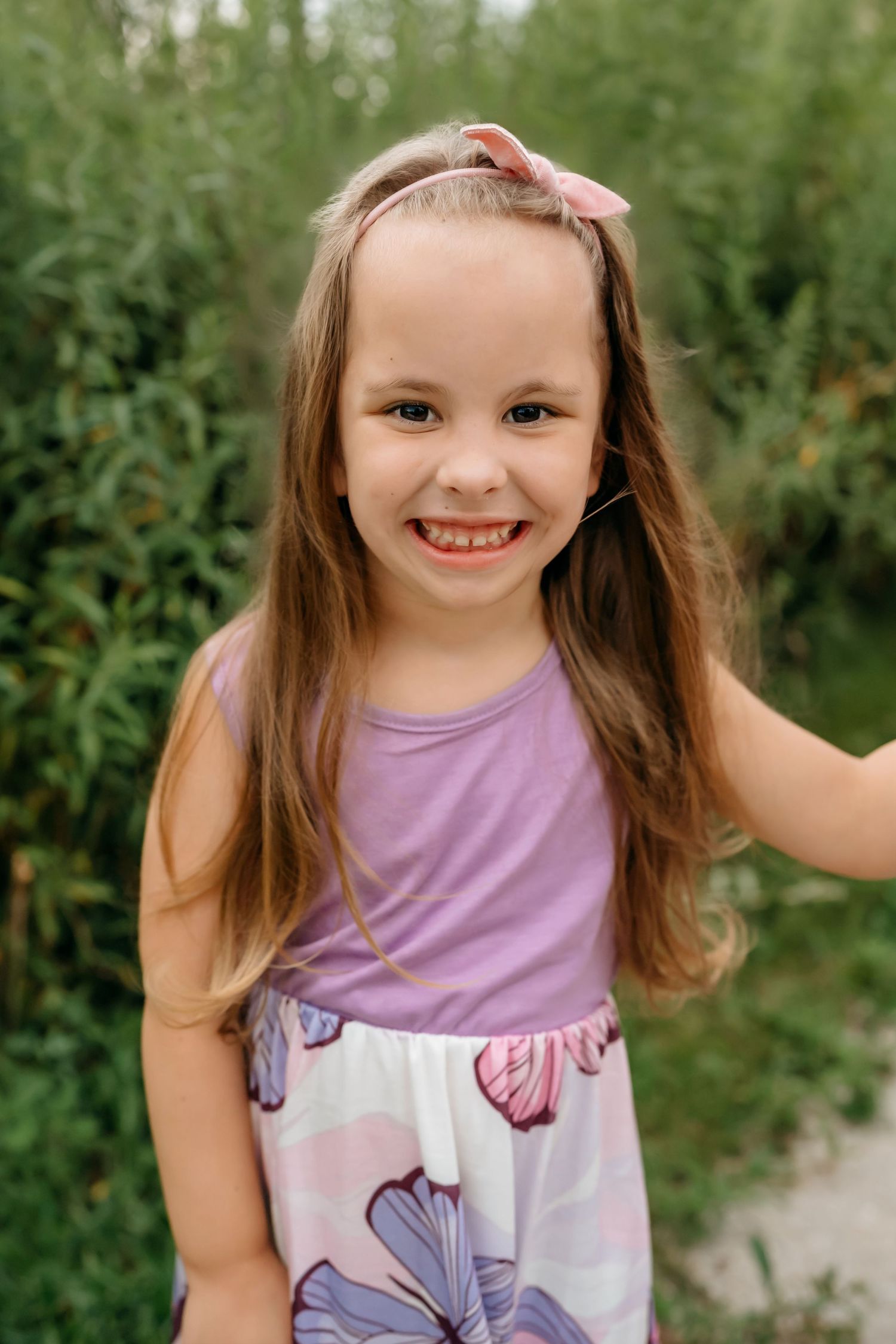 A series of four progressive photos showing a child wearing a purple tank top in a natural outdoor setting.