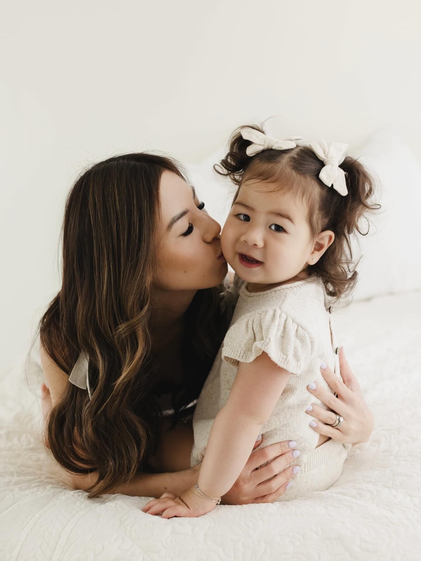 A touching series of intimate portraits showing gentle moments between parent and child on white bedding.