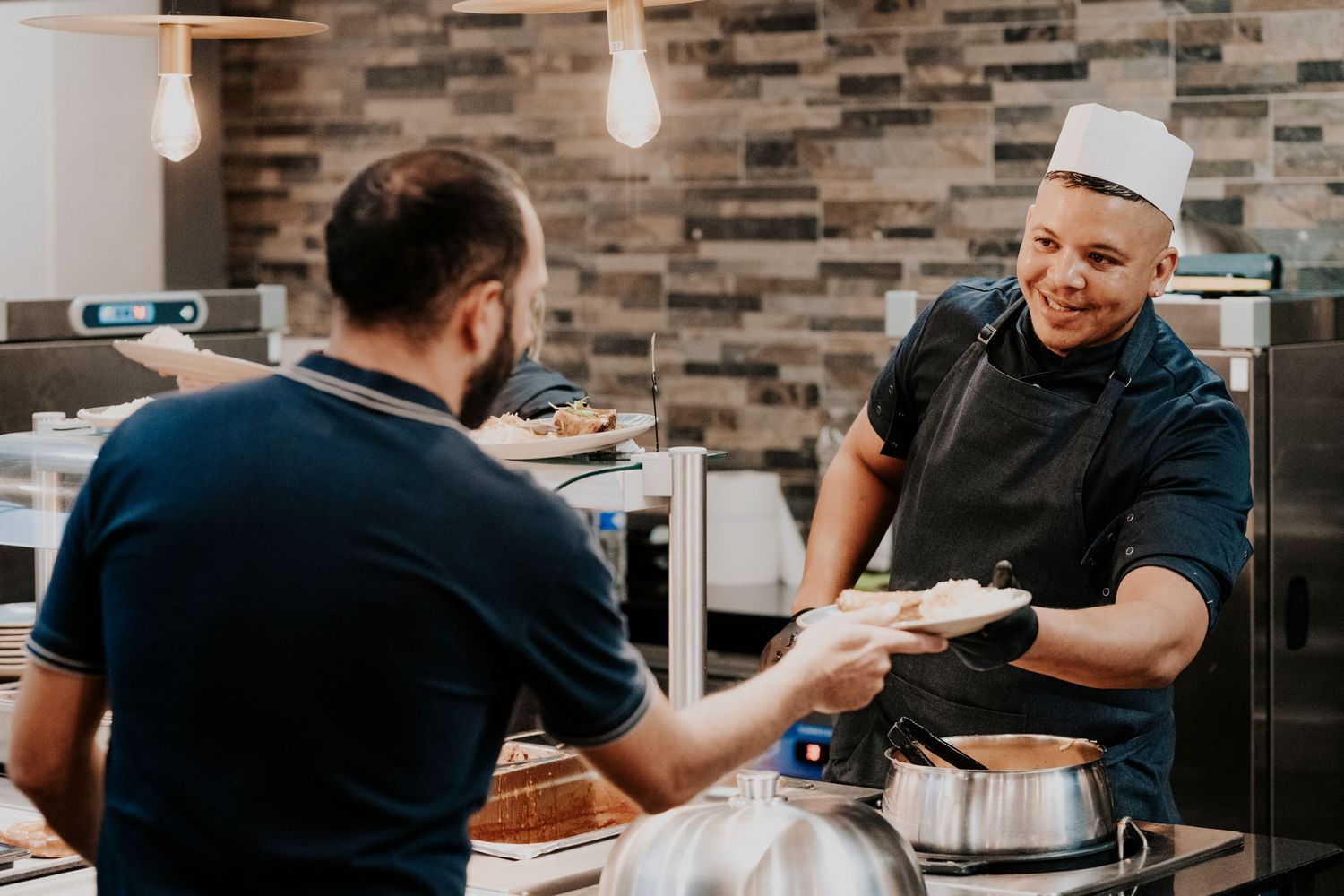 Reportage photo Toulouse: Employés de restaurant en cuisine préparant la nourriture et manipulant les plats pendant un service chargé.