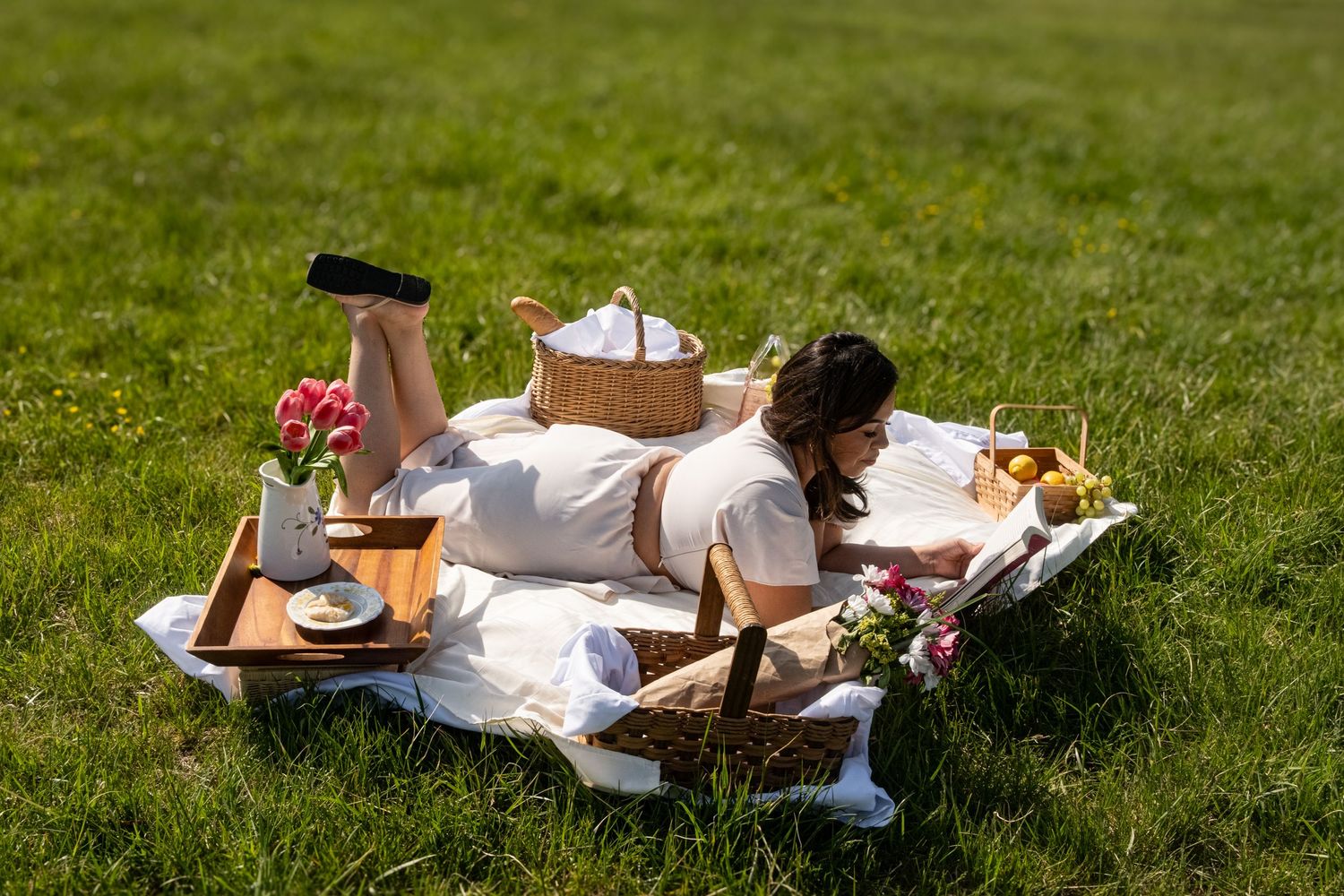 A picnic setup on green grass with blankets and refreshments.