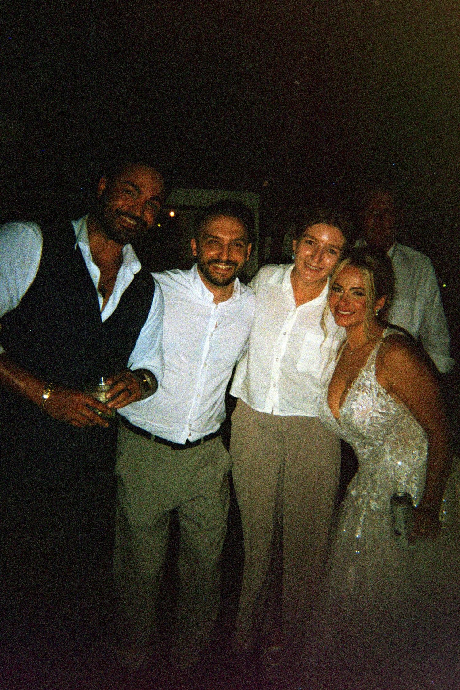 A group in formal attire celebrating at a dimly lit event with smiles and laughter.
