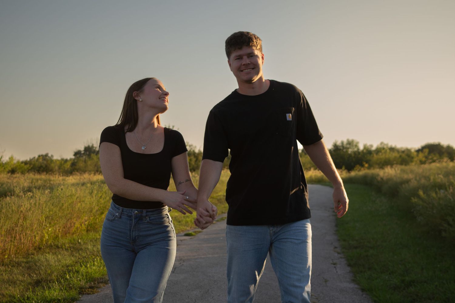 Couple walking on a trail at sunset while laughing with each other