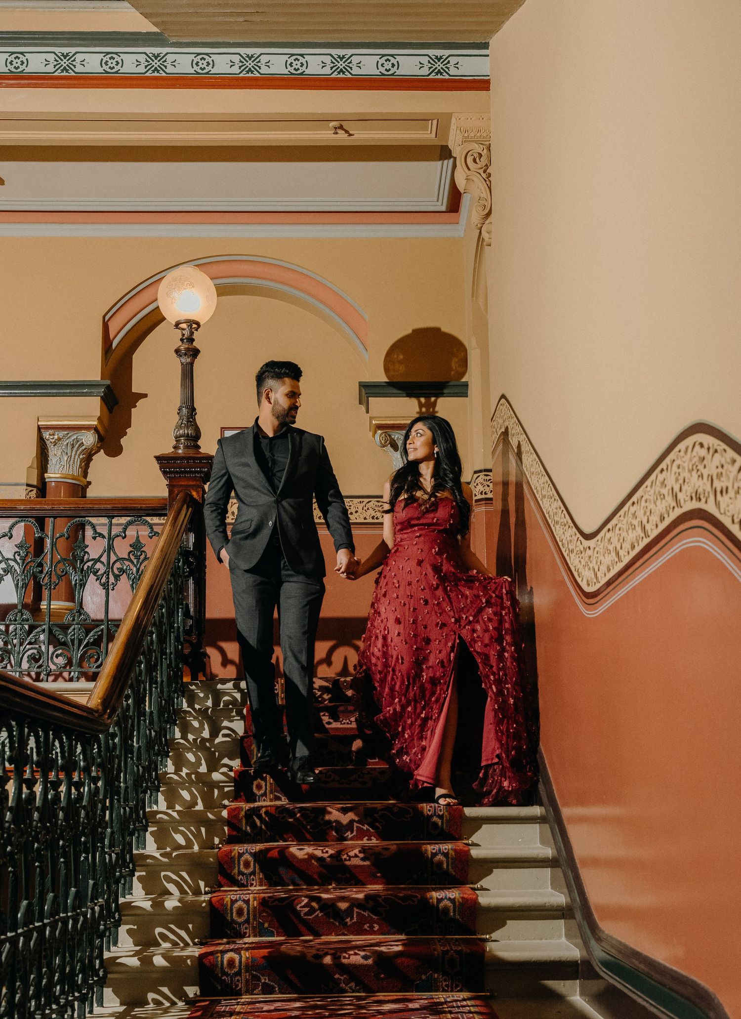 Series of cinematic frames showing a couple in formal attire posing on vintage staircase with ornate railings.