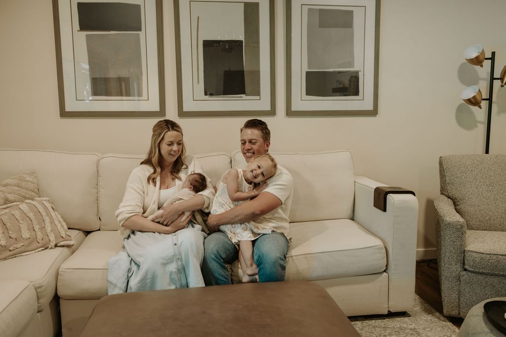 Family sitting together on a cream colored couch with framed artwork above.