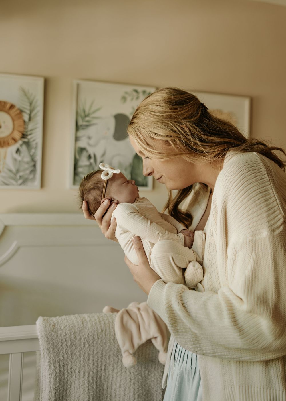 Close up of tender moment between parent and baby in cozy nursery with botanical prints.
