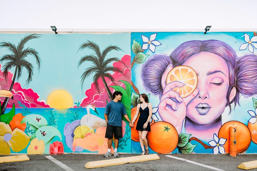 Vibrant street art mural featuring cheerful oranges and colorful tropical scenes painted on an outdoor wall.