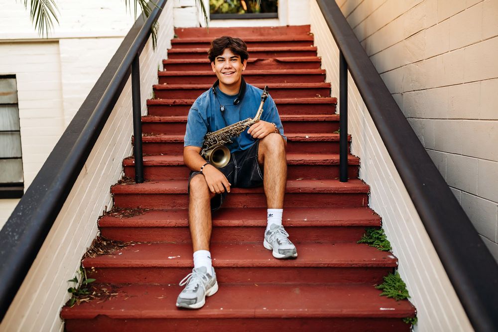 Person in blue shirt and khaki shorts sits in various positions on red painted outdoor stairs.