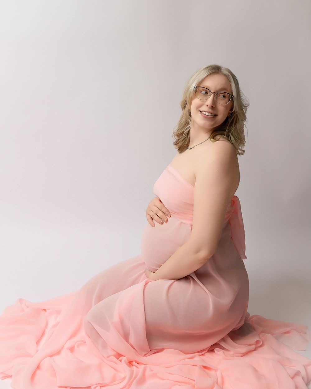 A series of feminine artistic portraits in neutral studio lighting with a flowing salmon pink dress.
