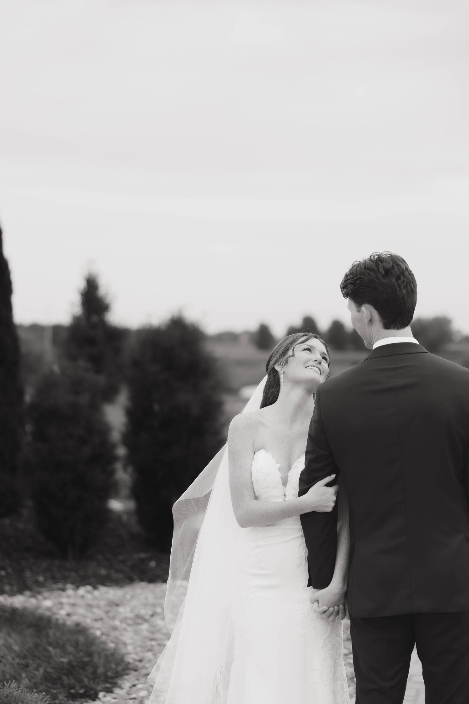 Black and white wedding portrait capturing an intimate moment between newlyweds outdoors.