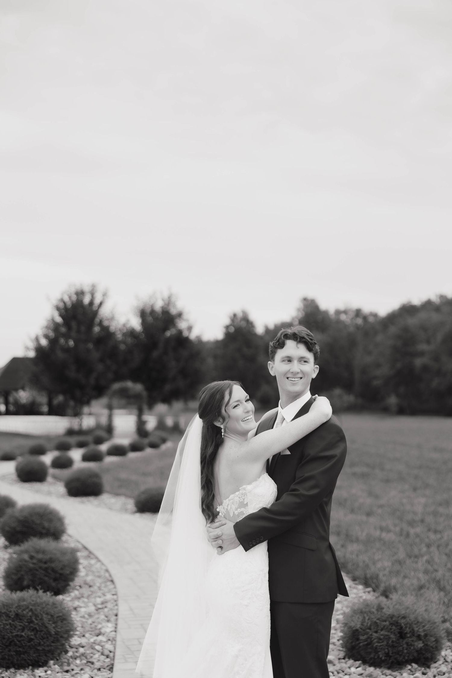 Black and white wedding portraits capture tender moments between newlyweds in a garden setting.