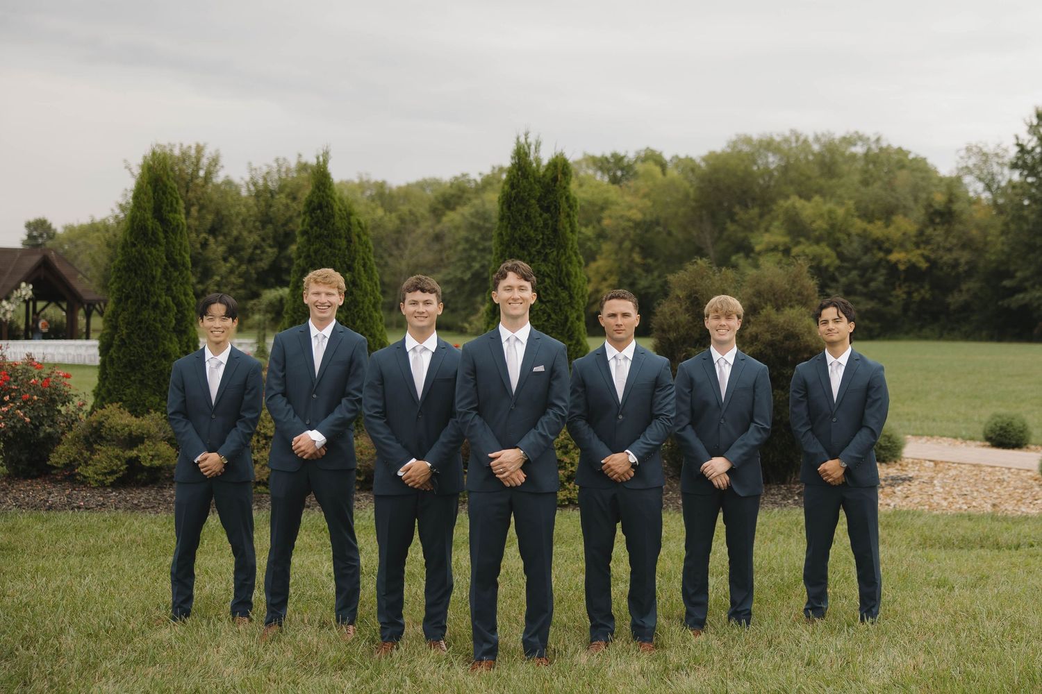 Groomsmen in navy suits pose together in a panoramic outdoor photo sequence.