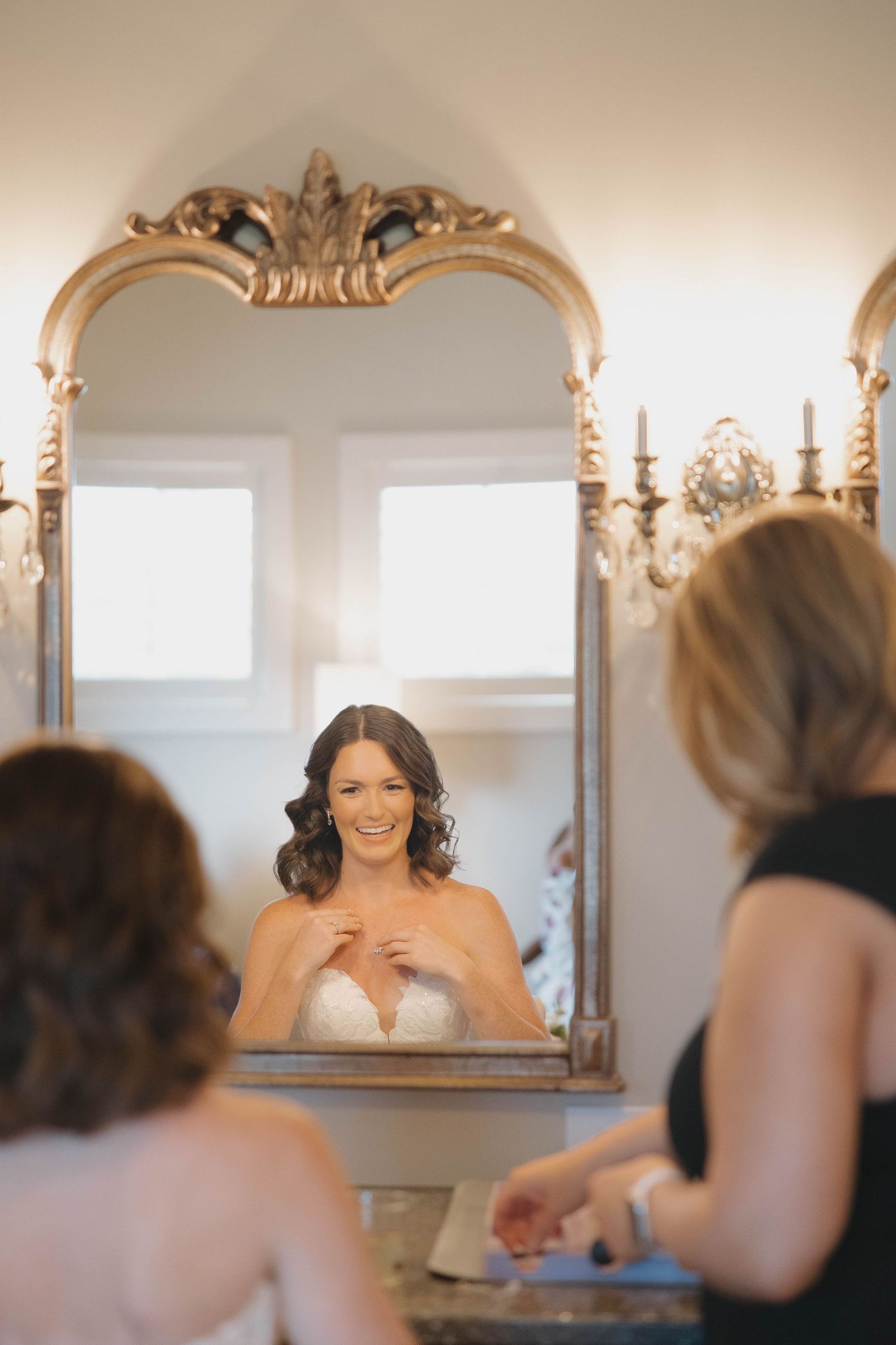 Woman admiring herself in an ornate classical mirror during preparations for a special event.