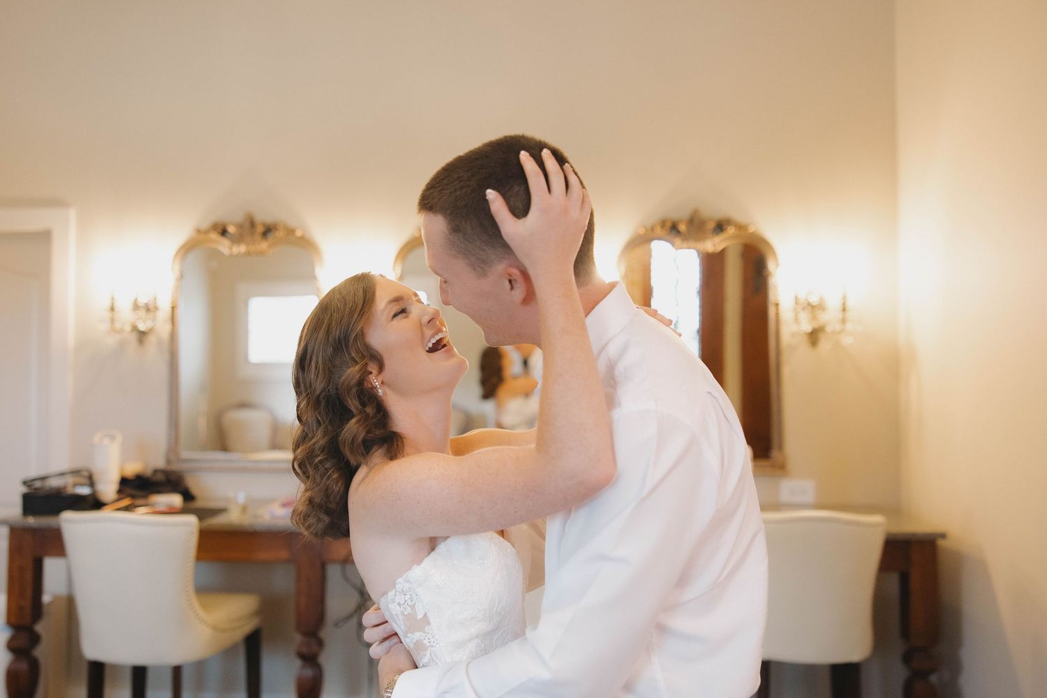Newlyweds share a joyful dance moment in an elegantly lit indoor venue.