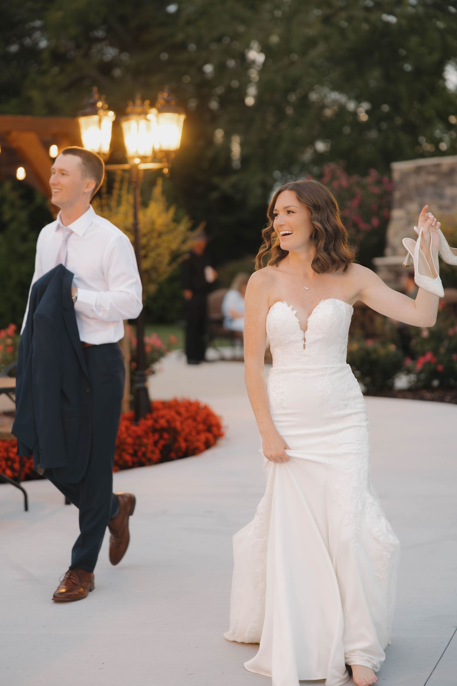 A couple and guests dance together during an outdoor evening wedding reception.