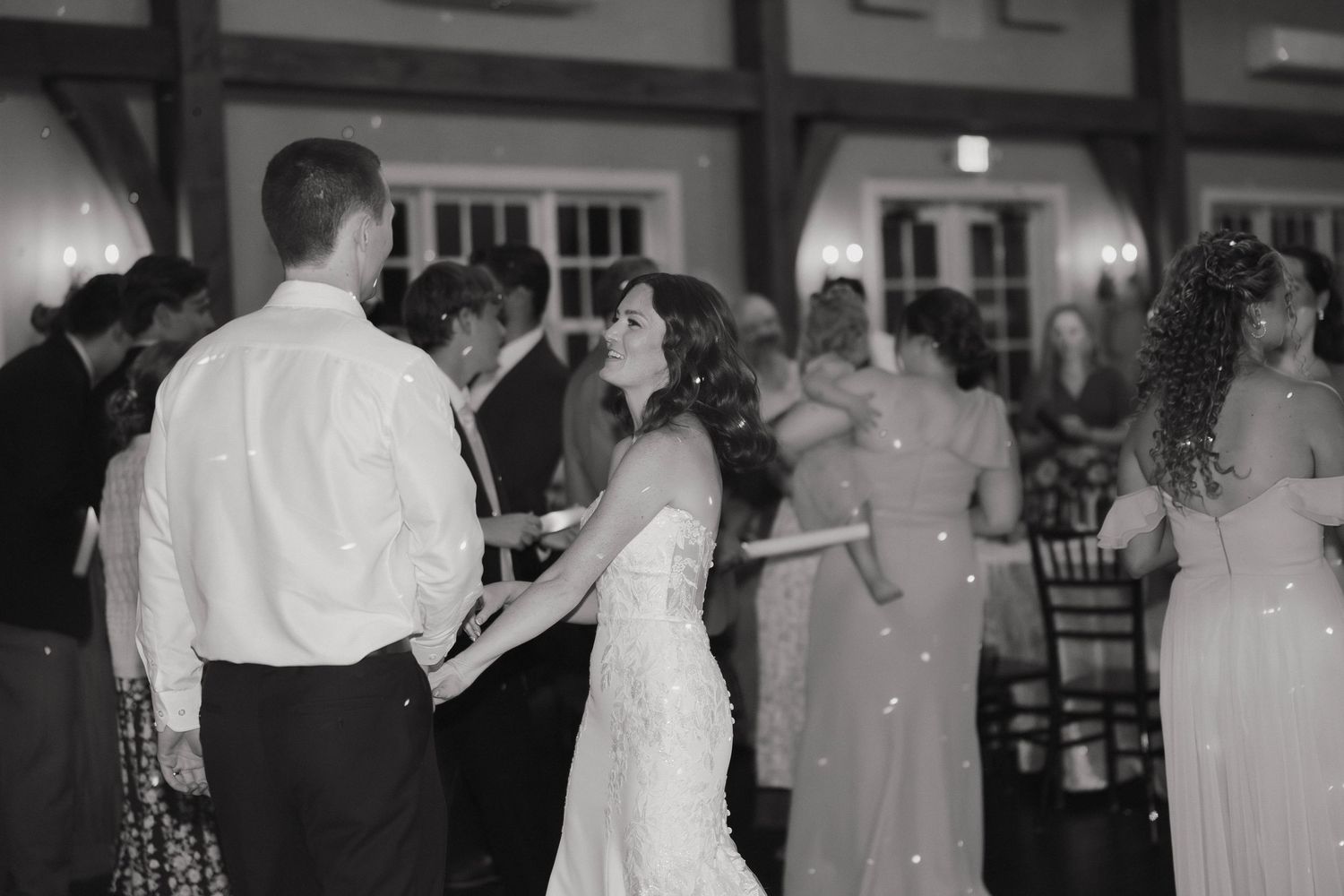 Couples slow dance together in a dimly lit ballroom at a formal evening celebration.
