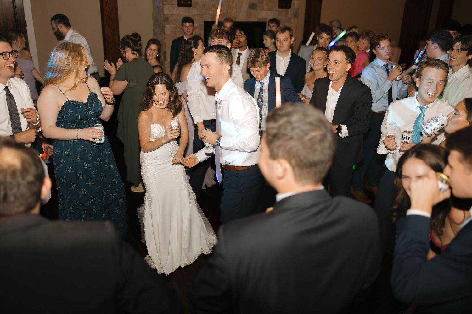 Wedding guests dance and celebrate together on a packed dance floor during an evening reception.