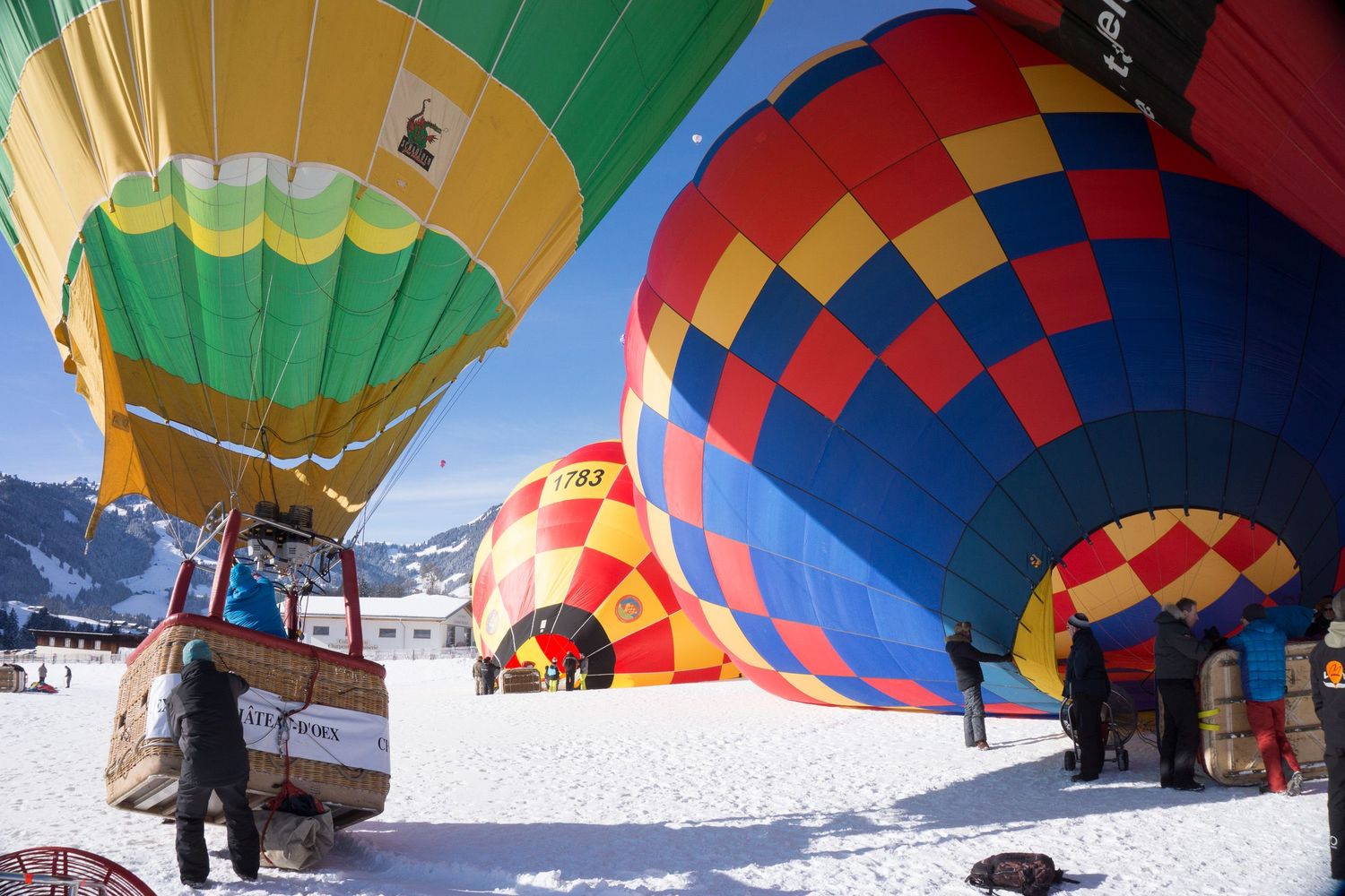 Colorful hot air balloons floating over a snowy mountain landscape against vibrant blue skies and white snow.