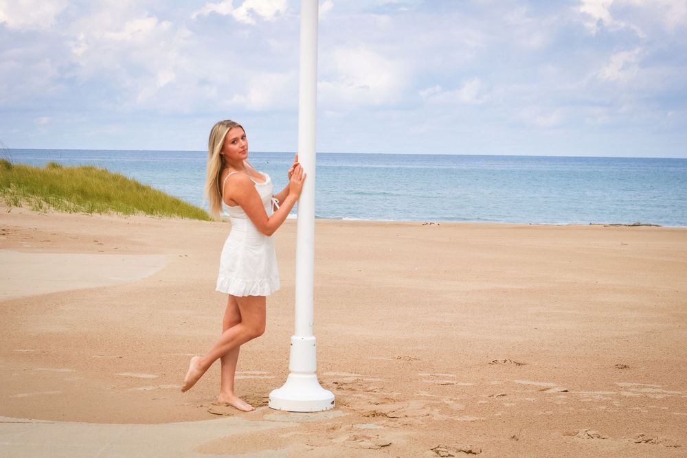 Serene beachscape with lighthouse and sandy shoreline under blue summer sky.