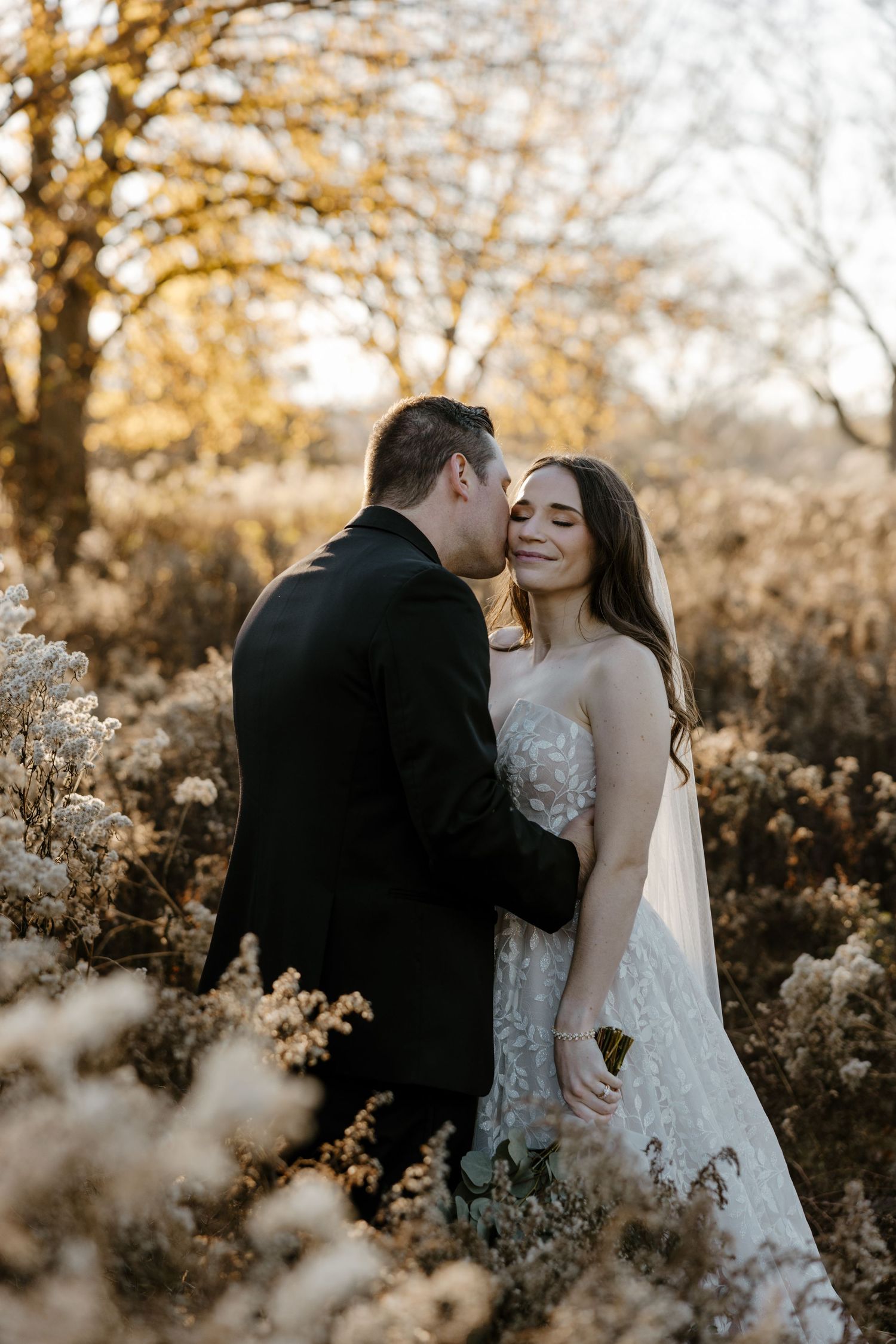 A couple embracing in a field of flowers during a golden sunset, creating a romantic and serene scene. Fort Worth Texas wedding photographer