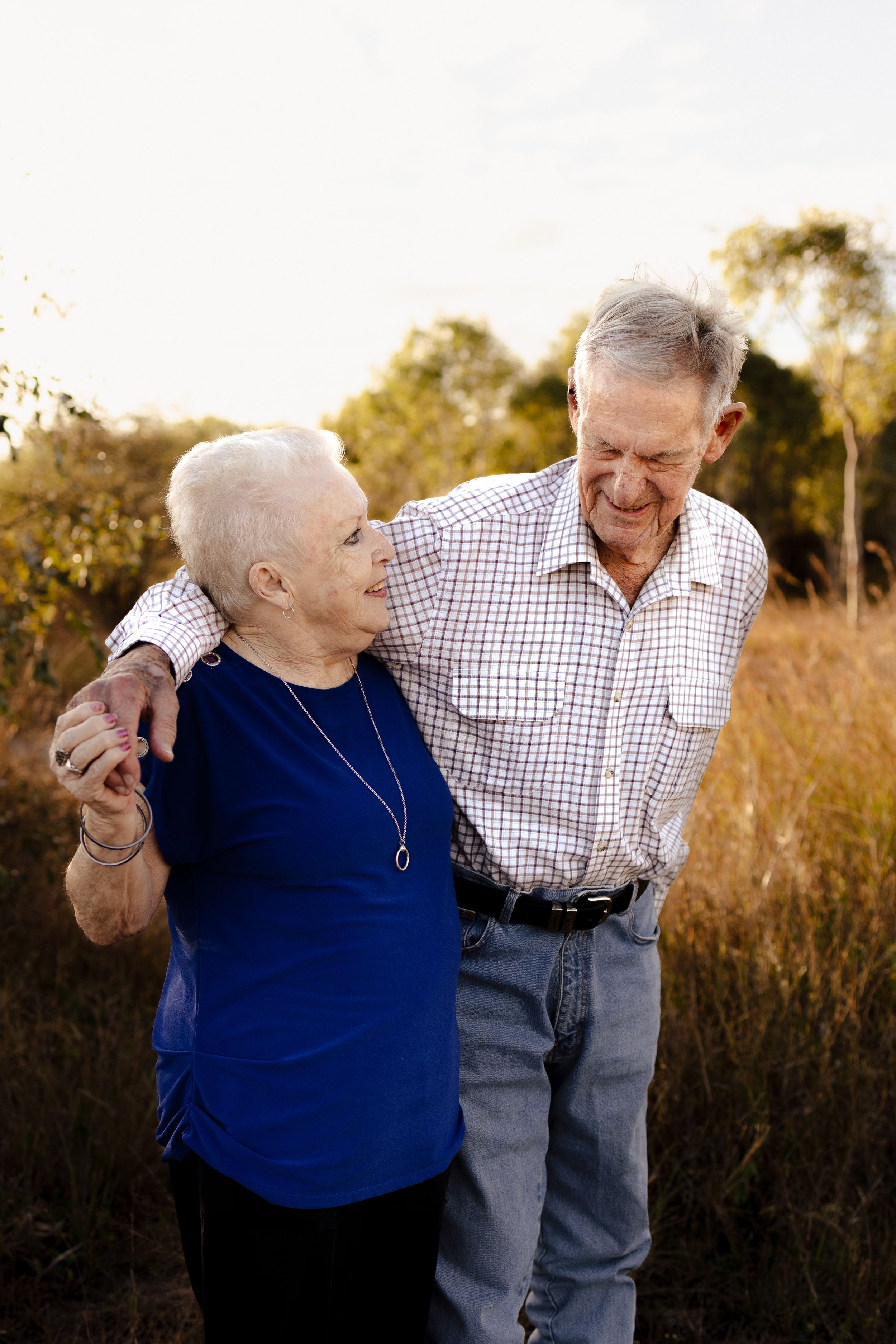 Senior couple dancing and laughing together in a sunlit autumn field.