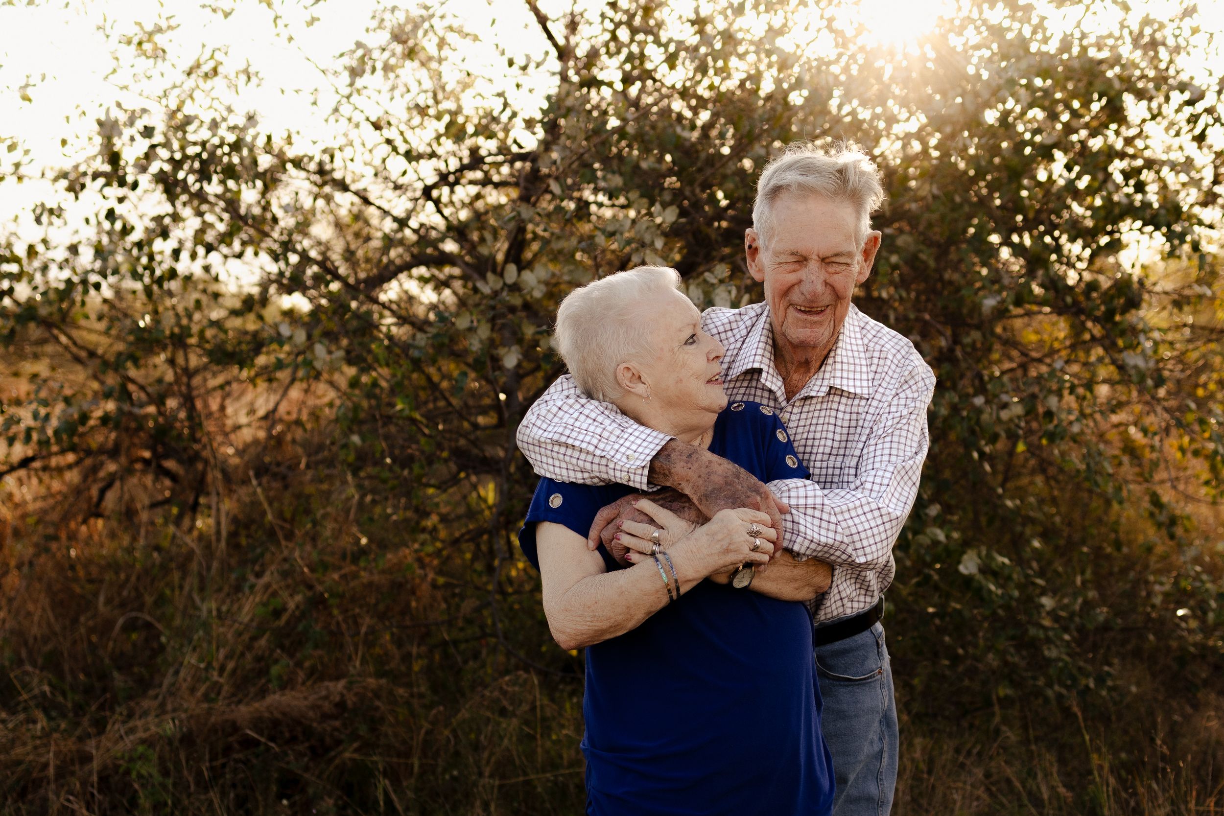 Senior couple sharing intimate moment outdoors with natural sunset lighting.