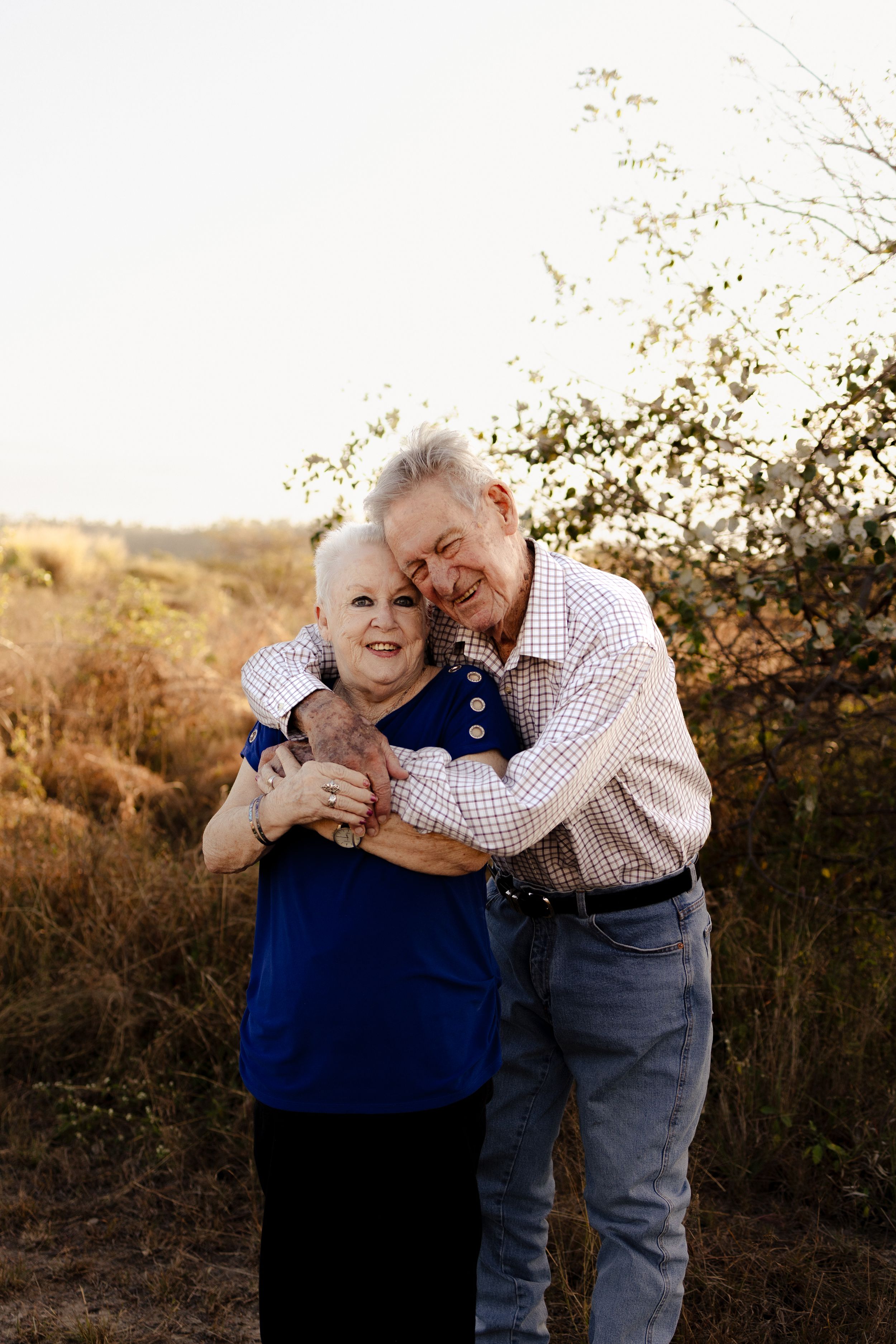 Senior couple sharing playful embrace against backdrop of autumn foliage.