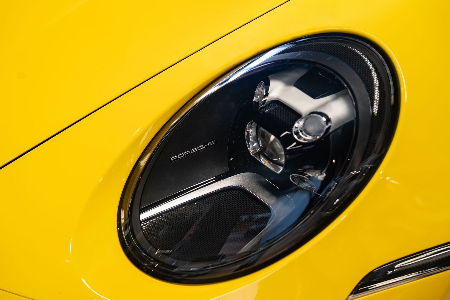Sleek black van door handle and side mirror detail against vibrant yellow background in automotive closeup shot.