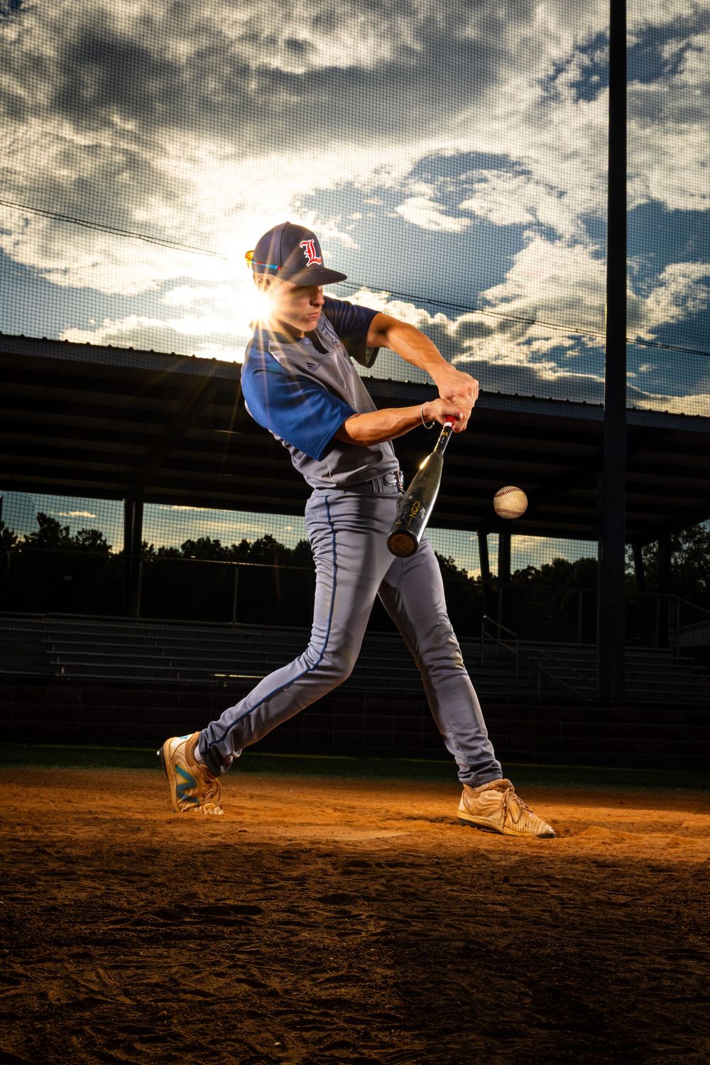 Baseball player swinging bat in sequence during sunset with dramatic cloudy sky at field.