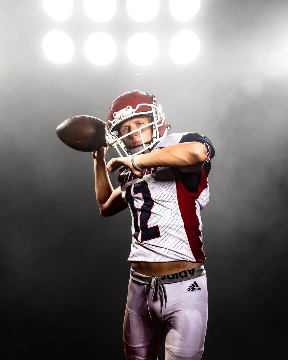 Football player catches the ball in white uniform against dark background with stadium lights in a dynamic sequence.
