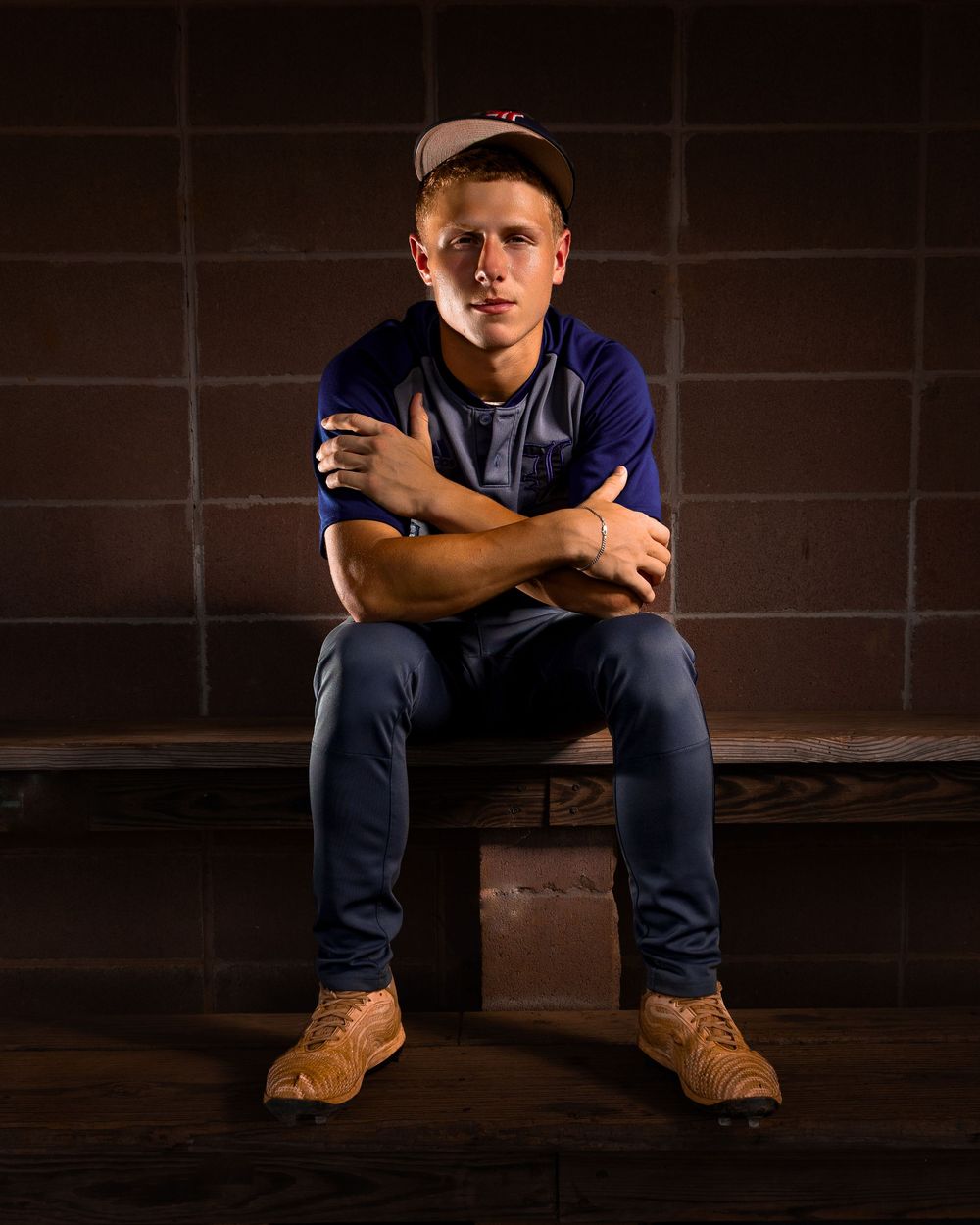 Person in casual attire sits on dark steps wearing tan work boots and navy pants in moody lighting.