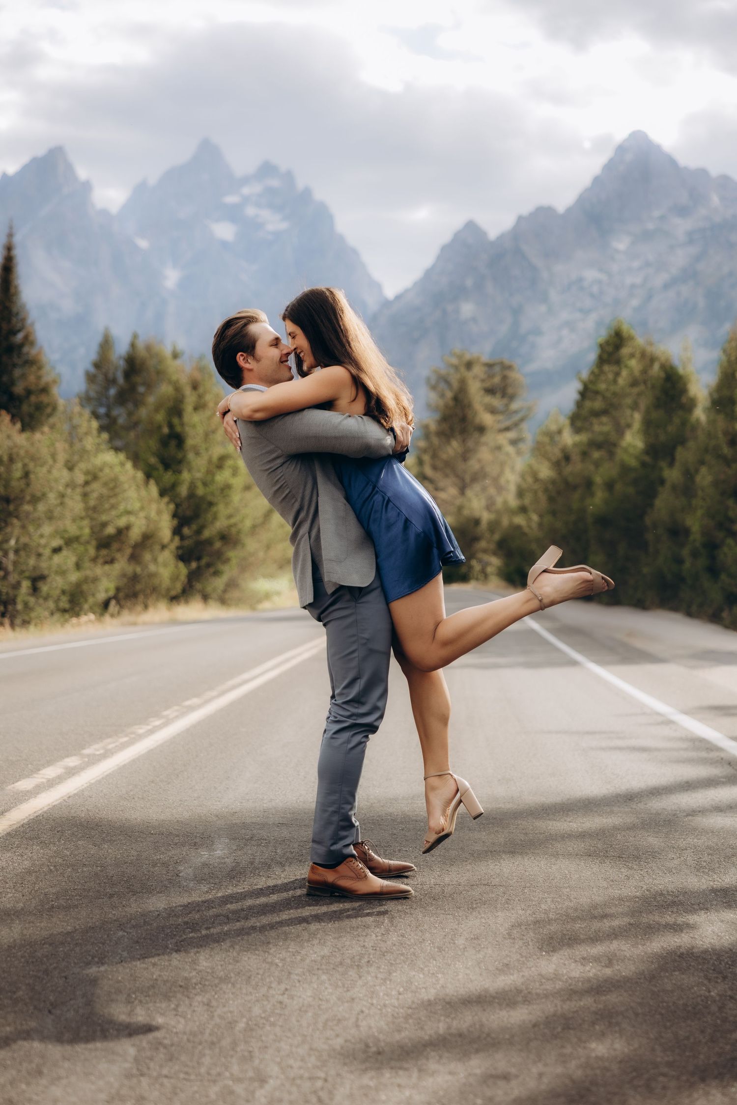 A romantic moment captured on a road with the majestic Grand Teton mountains rising in the background.