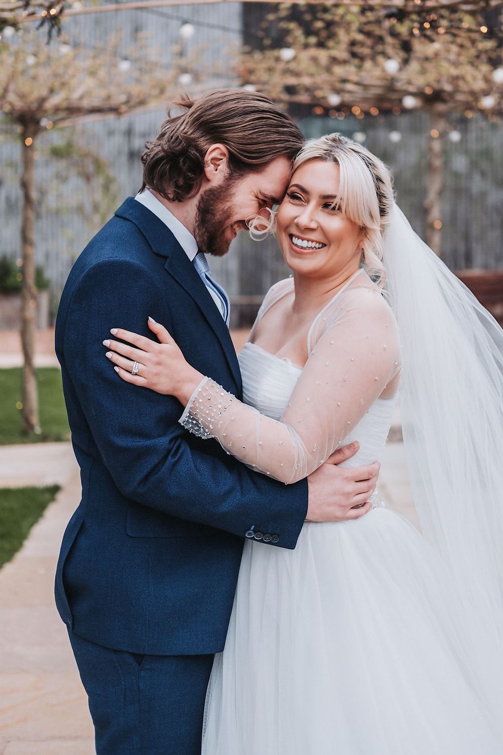 A couple in wedding attire share intimate embraces outdoors in a garden setting.