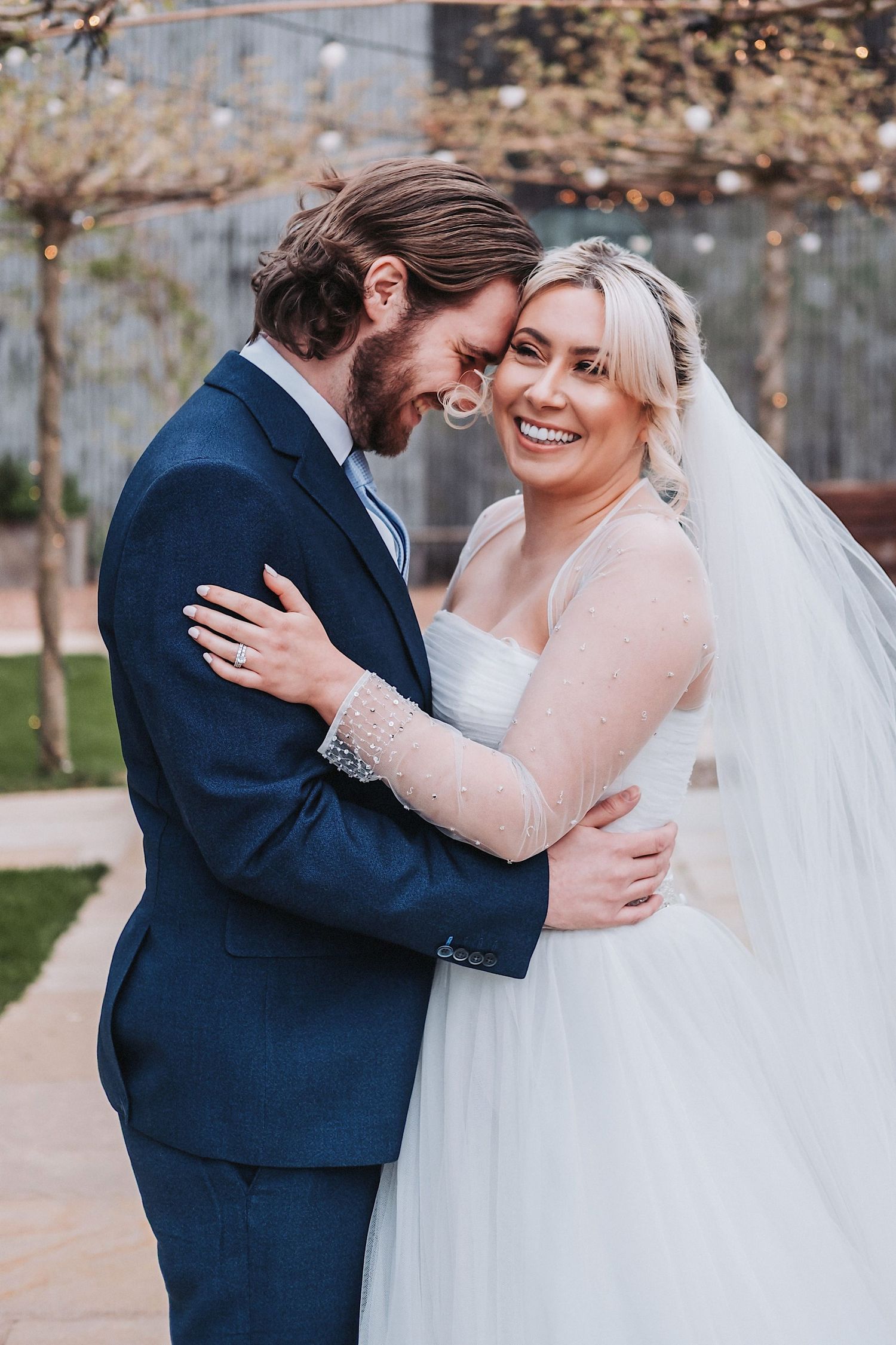 A couple in wedding attire share intimate embraces outdoors in a garden setting.