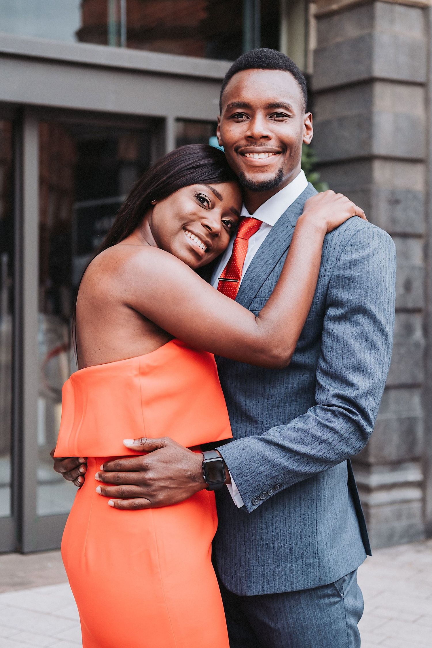 Three heartwarming engagement photos show a couple in an orange dress and grey suit embracing on a city street.
