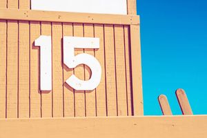 Geometric patterns formed by wooden lifeguard tower structure against vibrant blue sky.