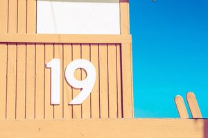 Minimalist composition of numbered beach tower details against bright blue sky.