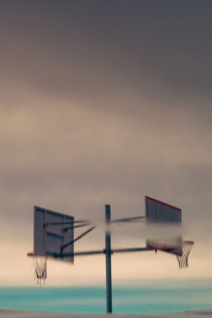 Two basketball hoops face each other in a dreamy teal and beige minimalist composition.