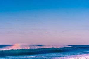 Crystal clear blue waves break in perfect formation under bright sunny skies.
