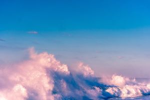 Panoramic view of fluffy white clouds against a vibrant blue sky during golden hour.