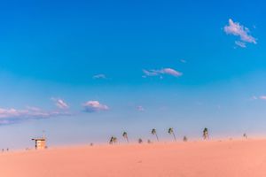 Row of wind turbines silhouetted against a bright blue sky with scattered clouds.