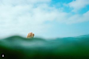 Ocean horizon line with subtle waves and cloudy sky in soft blue tones.