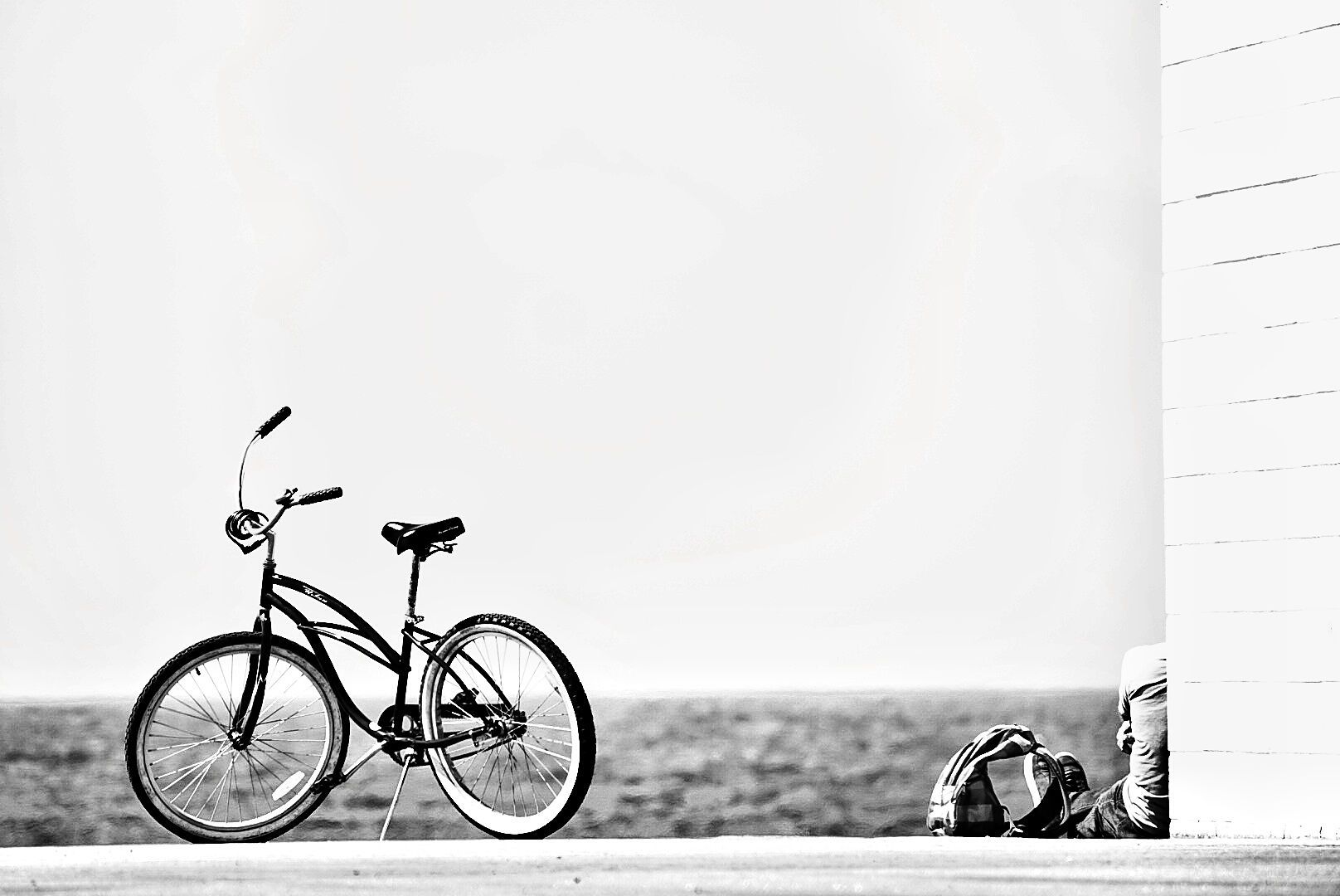 A vintage bicycle stands silently against a white wall in black and white artistic composition.