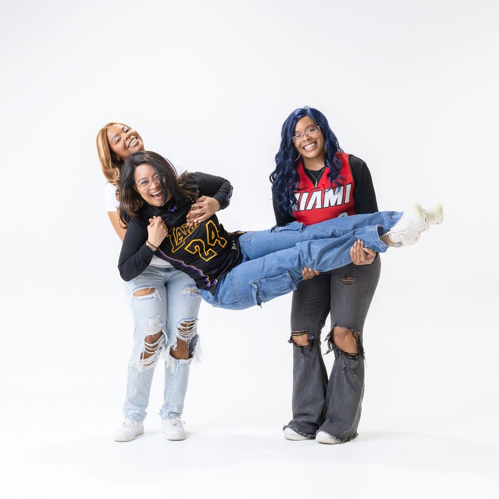 Two friends in denim and casual wear strike playful poses against a white background.
